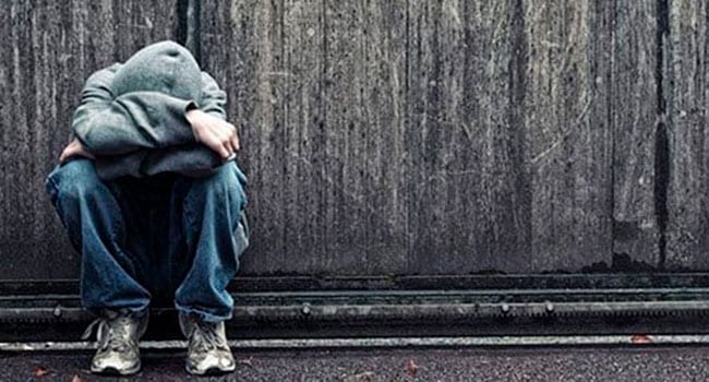 Depressed young man sitting on a curb