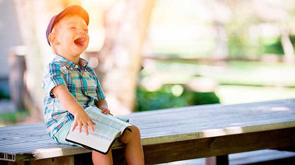 Child laughing and reading a book